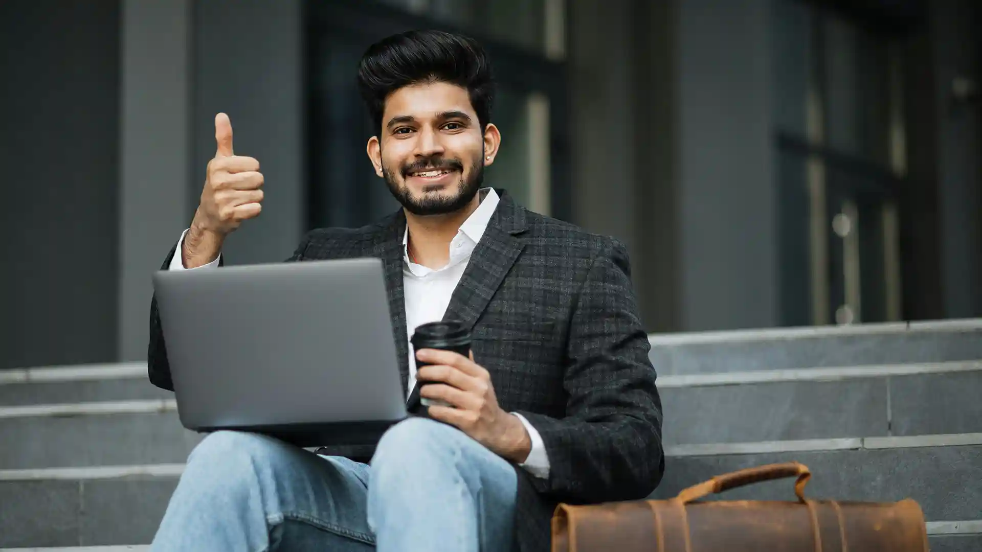 Man sitting on a staircase with a laptop in his lap.