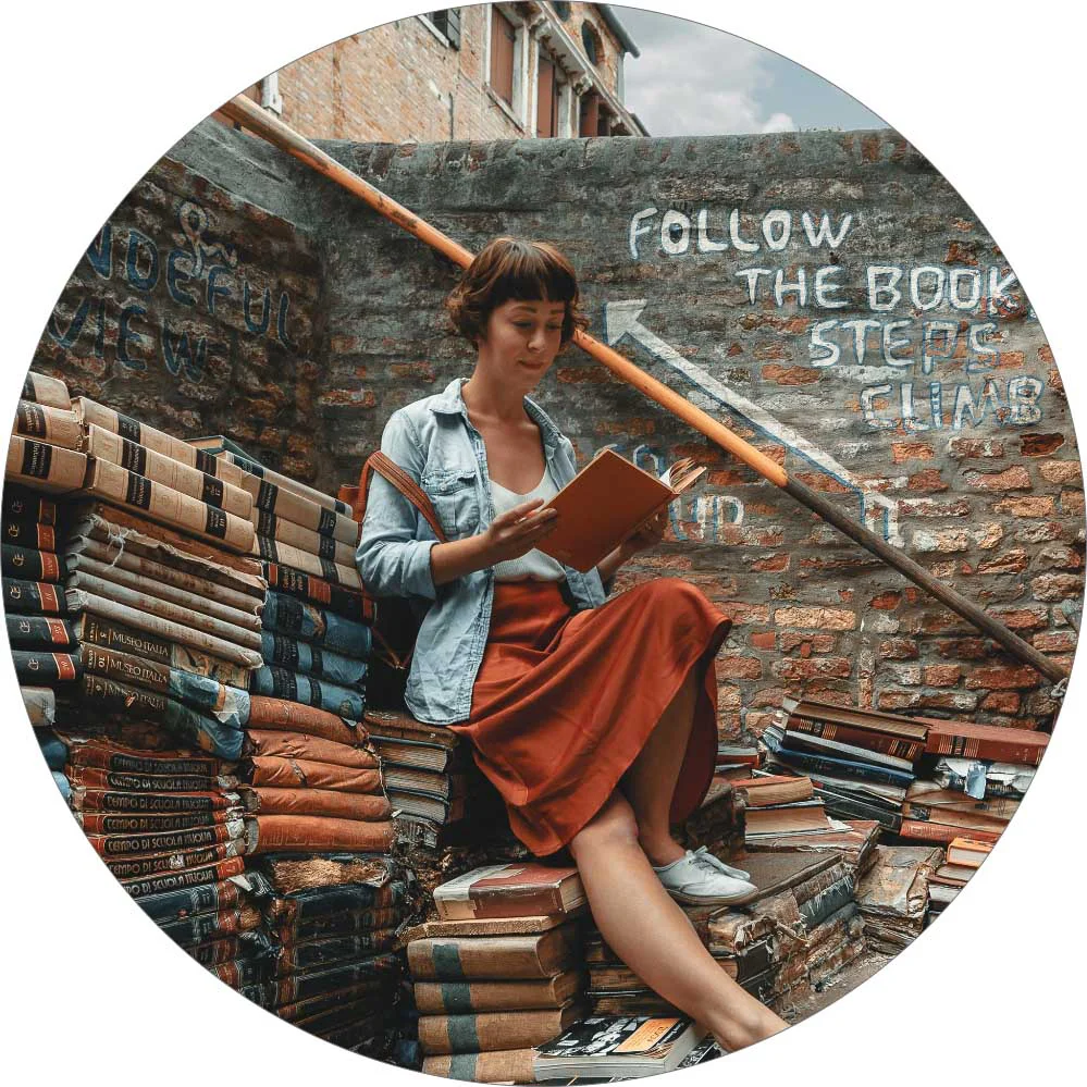 A woman is reading and sitting on the stairs